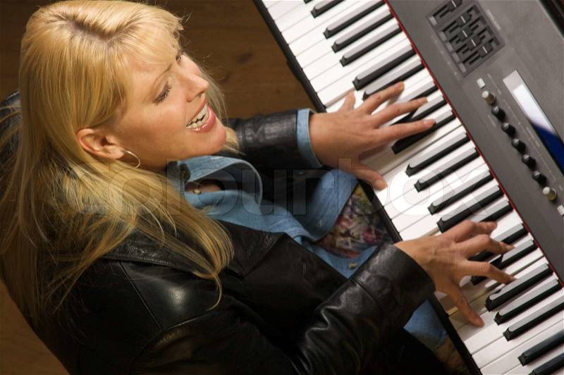 Female Musician Sings While Playing Digital Piano, stock photo