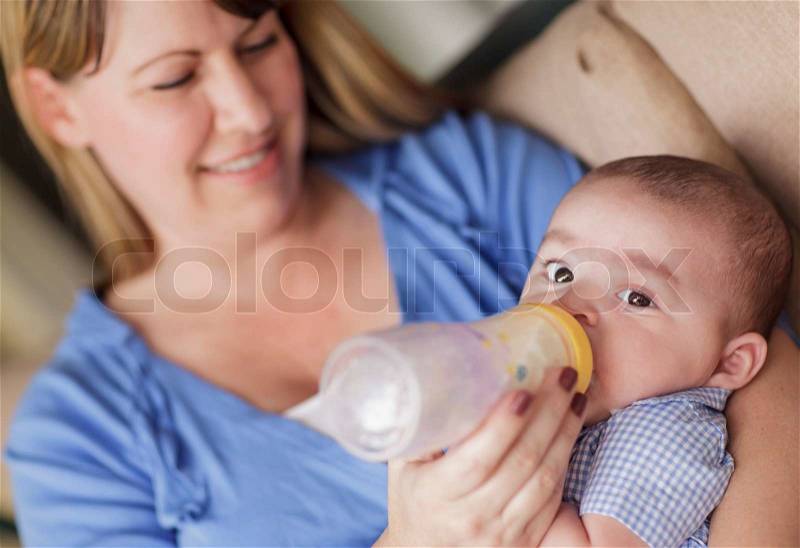 Happy Mother Bottle Feeding Her Very Content Son, stock photo