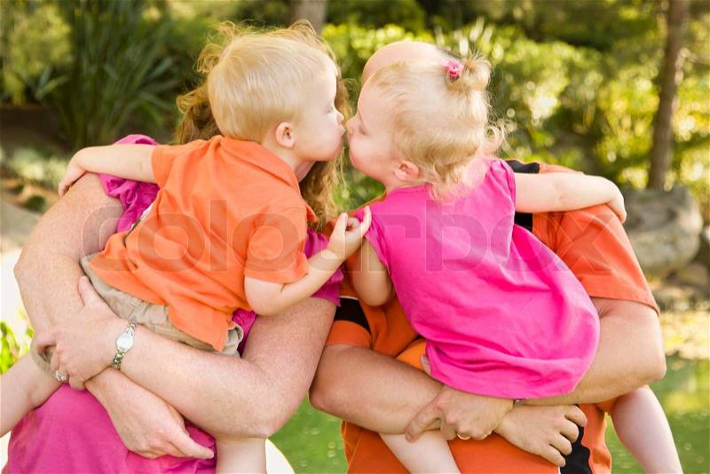 Mom and Dad Holding Kissing Brother and Sister Toddlers in the Park, stock photo