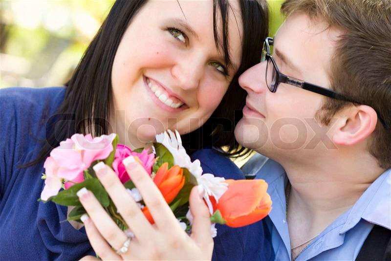 Attractive Young Man Gives Flowers to His Fiance Wearing the Engagement Ring, stock photo