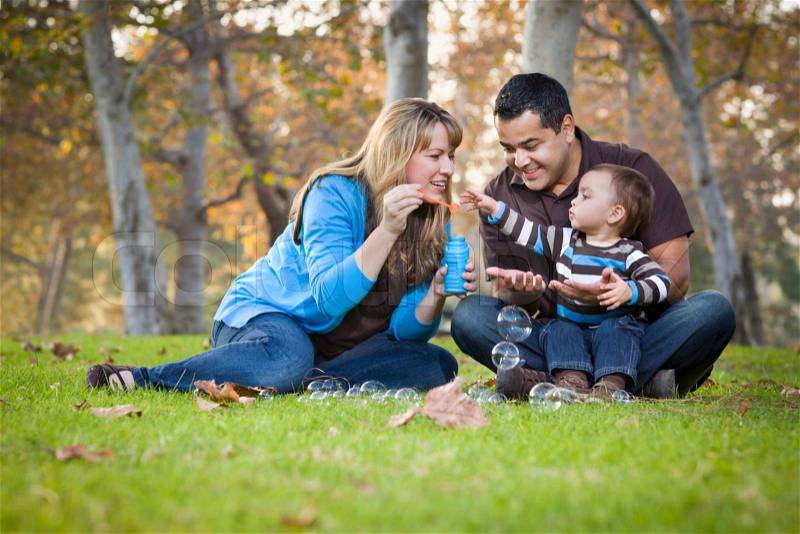 Happy Young Mixed Race Ethnic Family Playing Together with Bubbles In The Park, stock photo