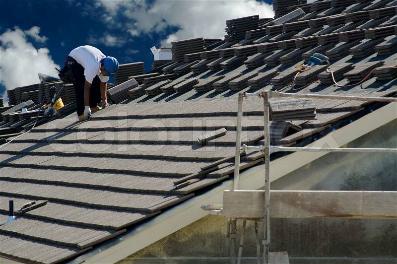 Roofer Laying Tile Shingles on a New Home, stock photo