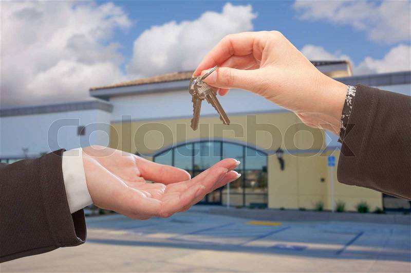 Real Estate Agent Handing Over the Keys in Front of Vacant Business Office, stock photo