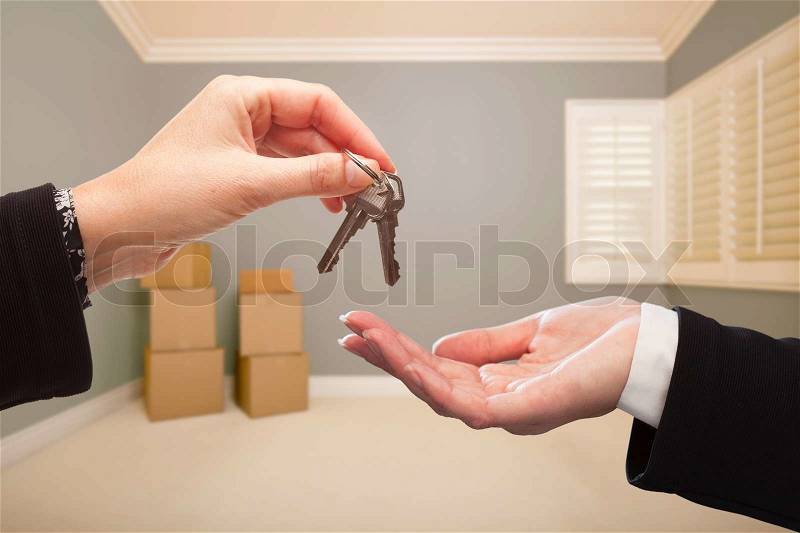 Woman Handing Over the House Keys To A New Home Inside Empty Grey Colored Room, stock photo