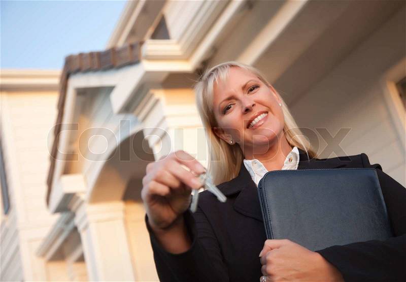Female Real Estate Agent Handing Over Keys in Front of Beautiful House, stock photo