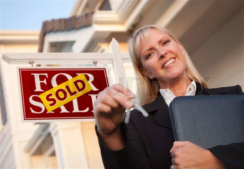 Female Real Estate Agent with Keys in Front of Sold Sign and Beautiful House, stock photo