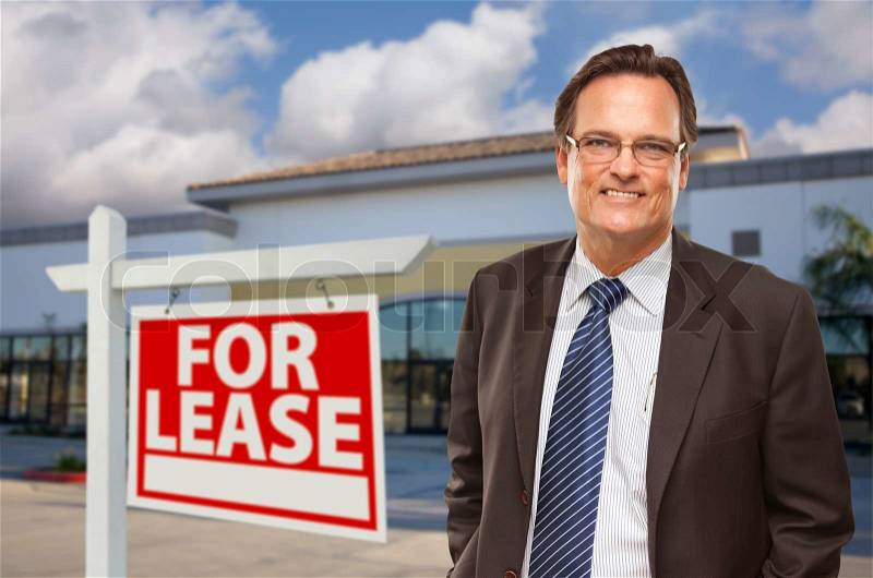 Handsome Businessman In Front of Vacant Office Building and For Lease Real Estate Sign, stock photo