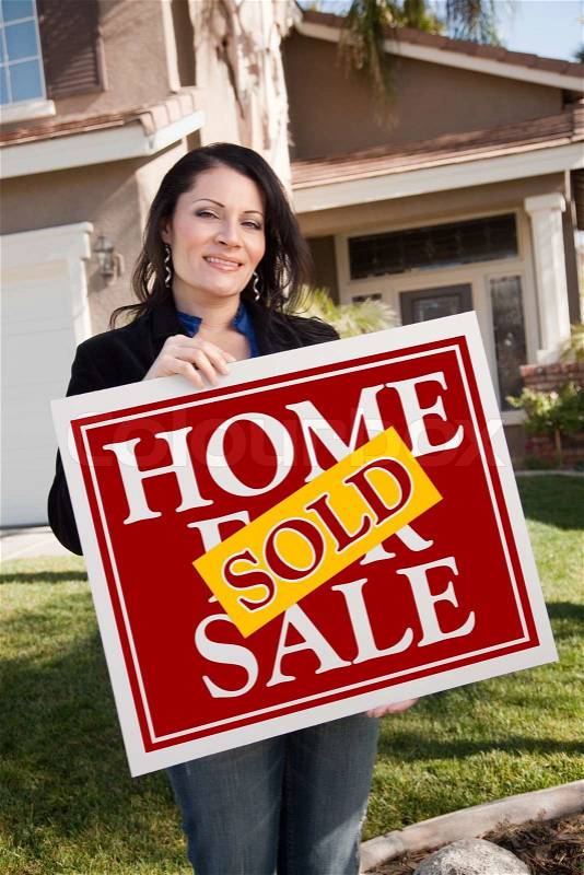 Happy Attractive Hispanic Woman Holding Red Sold Home For Sale Sign In Front of House, stock photo