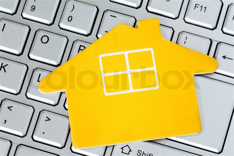 Paper house icon on the computer keyboard. Web hosting or real estate on the internet concept, stock photo