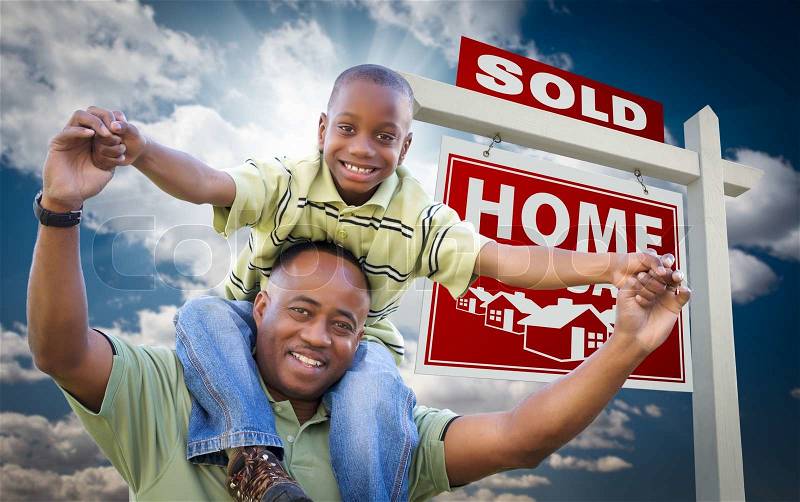 Happy African American Father with Son In Front of Sold Home For Sale Real Estate Sign and Sky, stock photo