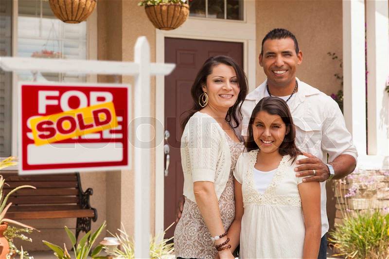 Hispanic Mother, Father and Daughter in Front of Their New Home with Sold Home For Sale Real Estate Sign, stock photo
