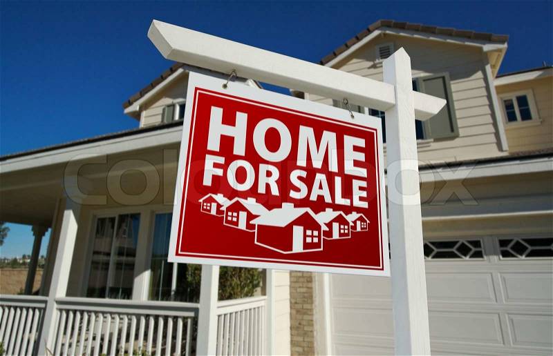 Red Home For Sale Real Estate Sign and House Against a Blue Sky, stock photo
