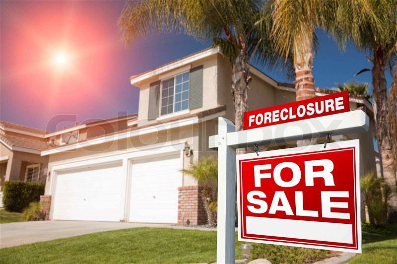 Red Foreclosure For Sale Real Estate Sign in Front of House with Red Star-burst in Sky, stock photo