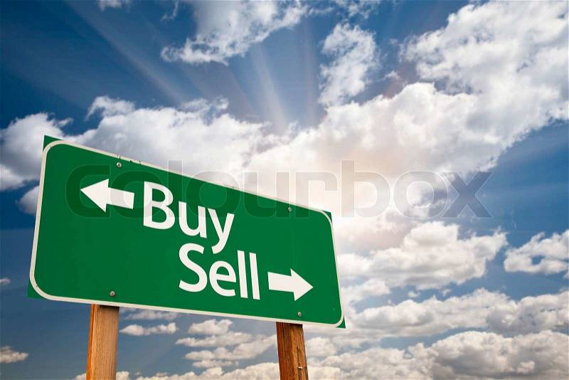Buy, Sell Green Road Sign Against Clouds and Sunburst, stock photo