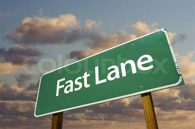 Fast Lane Green Road Sign Over Dramatic Clouds and Sky, stock photo