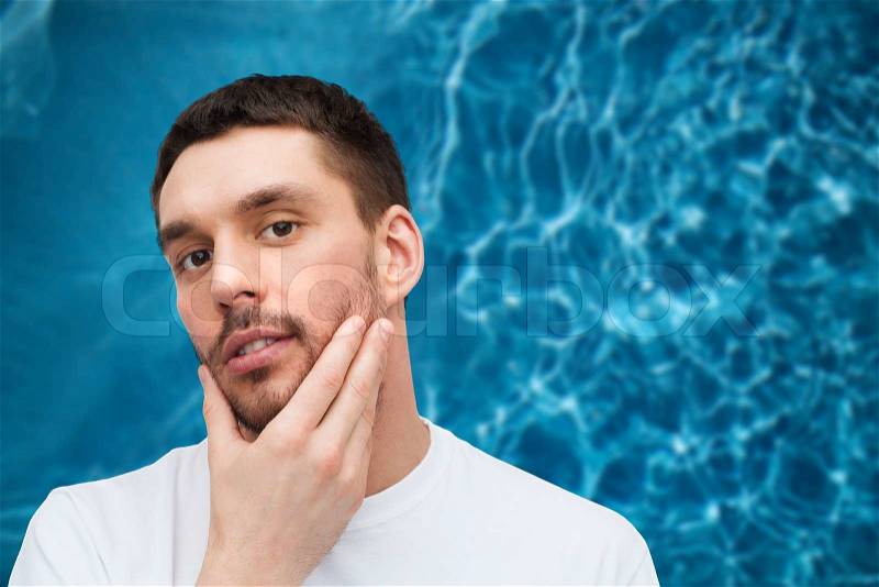 Health and beauty concept - beautiful calm man touching his face, stock photo