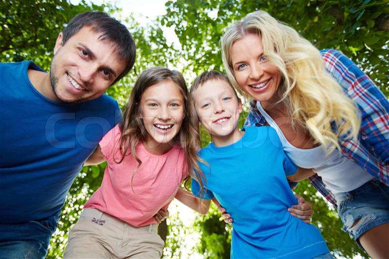 Photo of happy family of four looking at camera outdoors, stock photo