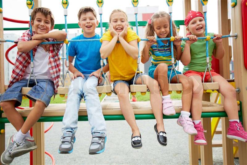 Happy friends sitting on swing and looking at camera, stock photo
