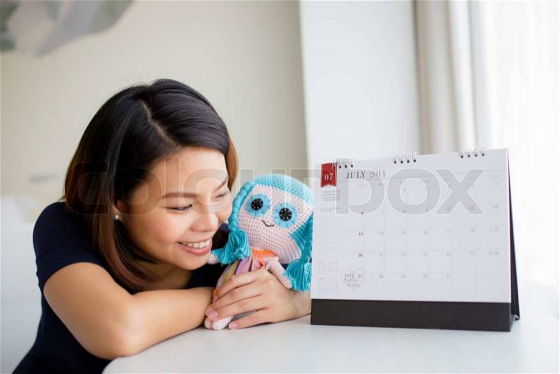 Beautiful pregnant woman looking at the calendar for the date of birth, stock photo