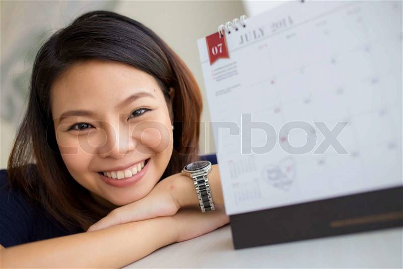 Beautiful pregnant woman looking at the calendar for the date of birth, stock photo