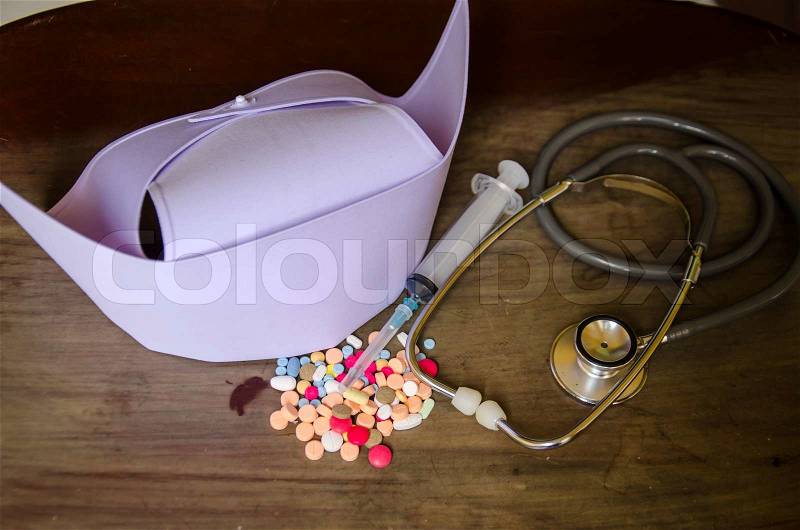 Stethoscope and nurse cap on wood with medicine, stock photo