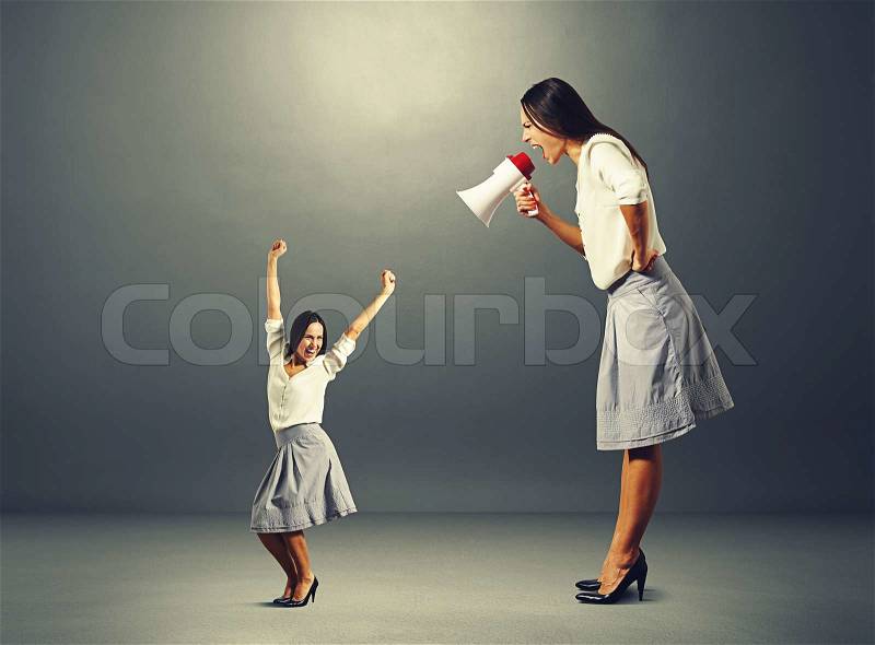 Jolly woman and angry big woman over dark background, stock photo