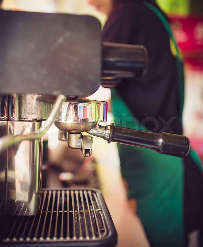 Prepares espresso in his coffee shop; close-up, stock photo