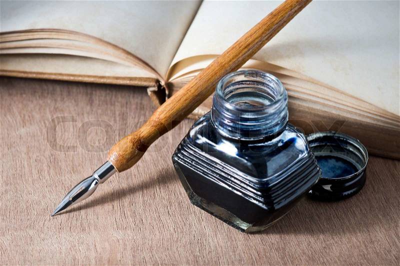 Still life photography, opening vintage book on wooden table with dip pen and inkwell, stock photo