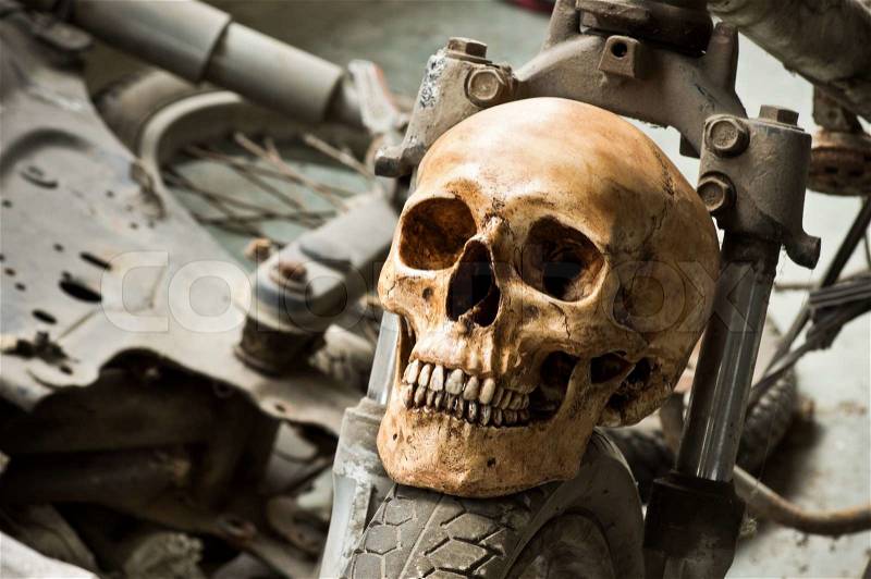 Still life photography, Human skull on front wheel of old motorcycle in junkyard concept, stock photo