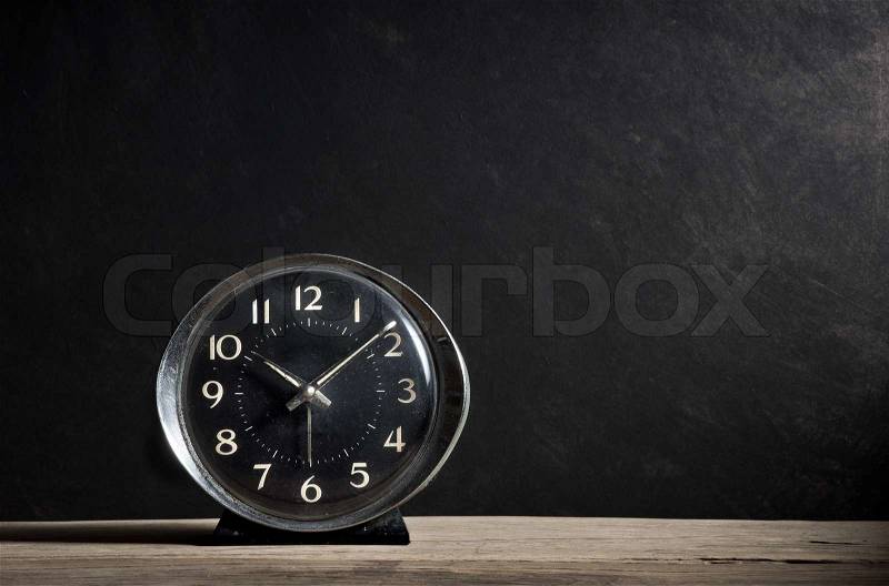 Old alarm clock on old wood plank with dark grunge background, stock photo