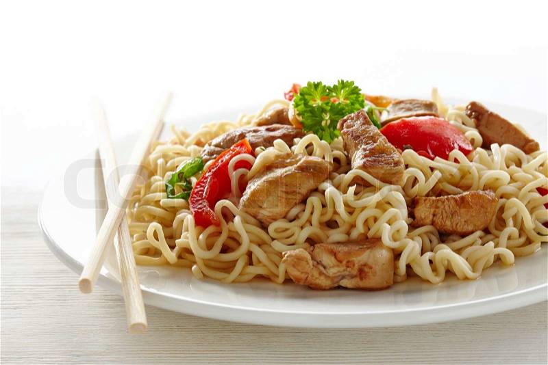 Noodles with chicken and vegetables on white plate, stock photo