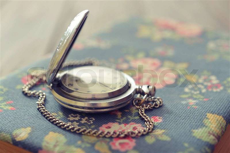 Vintage pocket watch on old book closeup, stock photo