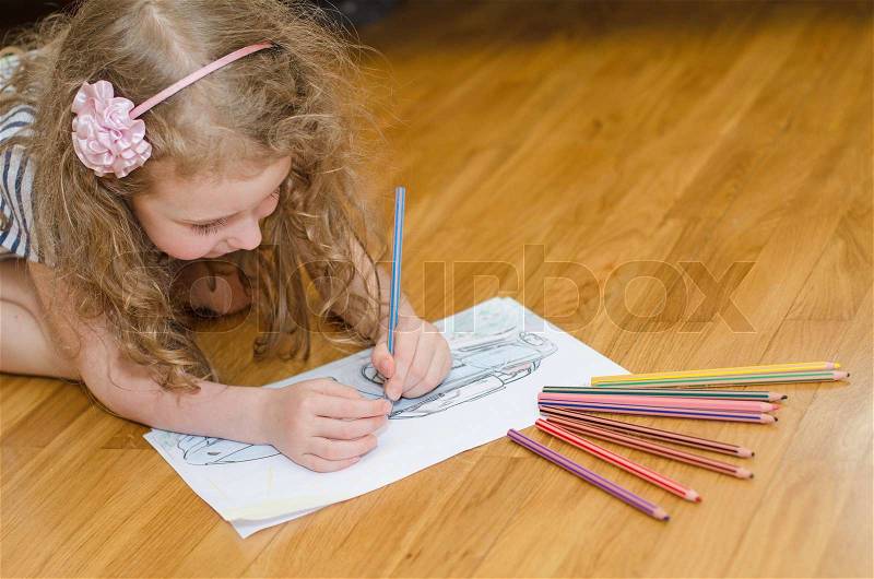 Little girl drawing car with colored pencils, stock photo