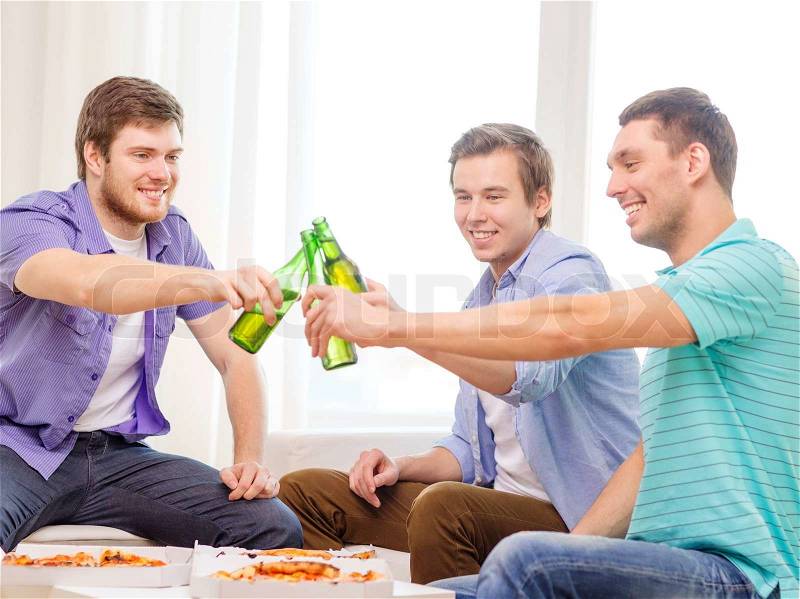 Friendship, food and leisure concept - smiling male friends with beer and pizza hanging out at home, stock photo