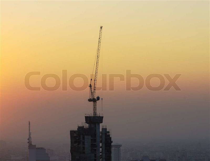 Buildings under construction with cranes and illumination at twilight time, stock photo