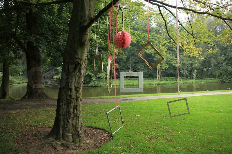 The frames in various sizes and different levels hanging on the branch from the tree in park in summertime, stock photo