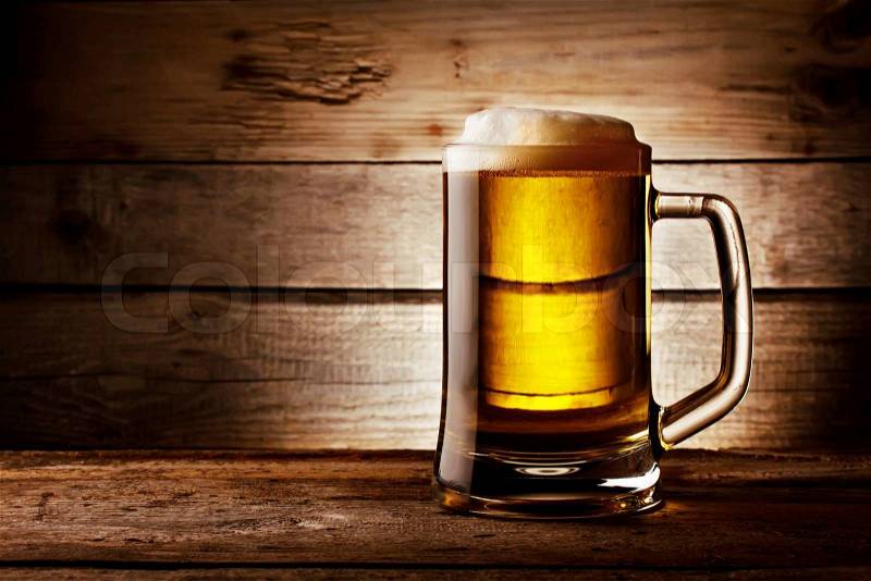 Filled with beer glass with foam on background of wooden planks, stock photo